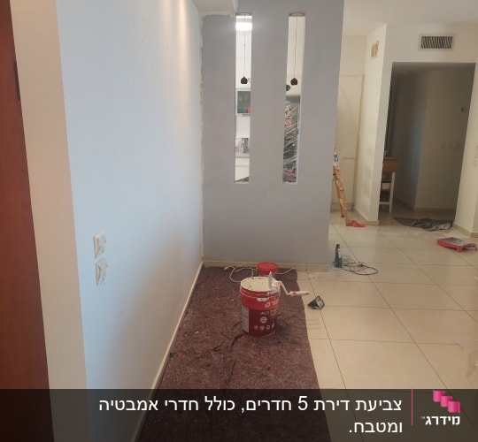 קיר צבוע עם דלי צבע וכלי עבודה על הרצפה